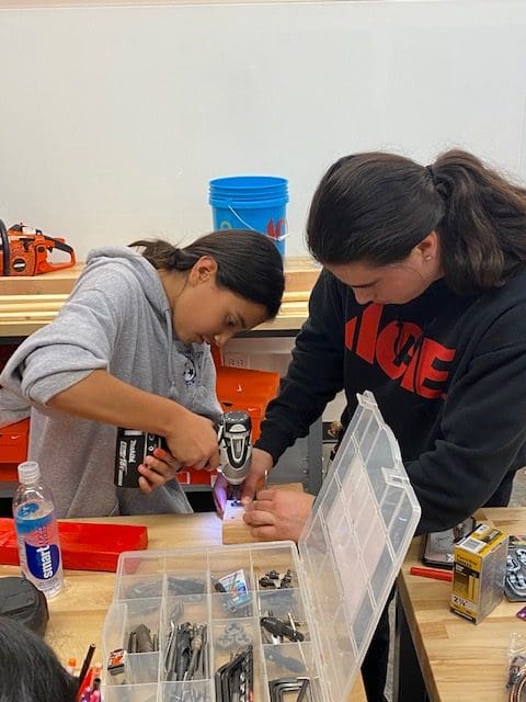 Two women working on a project in the middle of a room.